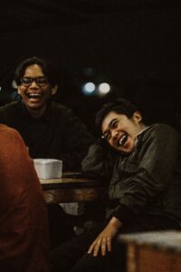 pexels-lukas-arianto-152146011-14155952 A trio of male friends are laughing together at night.