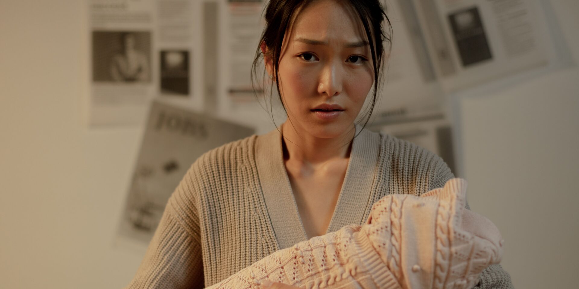 An Asian woman holding her newborn baby and looking distressed