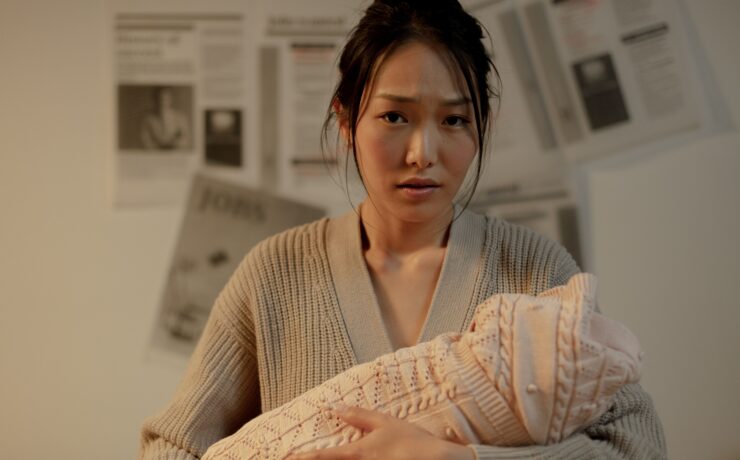 An Asian woman holding her newborn baby and looking distressed