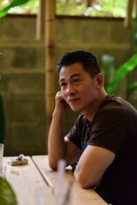 pexels-soc-nang-d-ng-2150345854-34973648 A middle-aged Asian man sitting at a park table and staring off into the distance