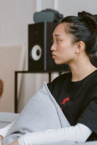 pexels-tima-miroshnichenko-7046688 A young Asian woman stares off into space looking worried.