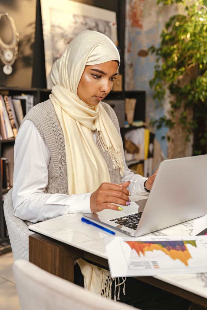 pexels-anthonyshkraba-production-8837519 A South Asian woman sits at a desk looking at her laptop.