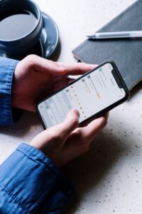 A pair of hands holds a smartphone. The phone screen displays social media comments that are unreadable.