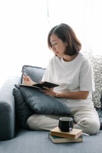 pexels-katya-wolf-8715932 An Asian woman sits on her couch writing in her journal with some tea.